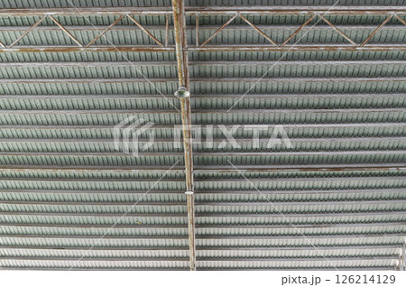 Industrial ceiling with exposed beams and structural elements in modern building, showing metal framework and lighting fixtures in organized pattern 126214129