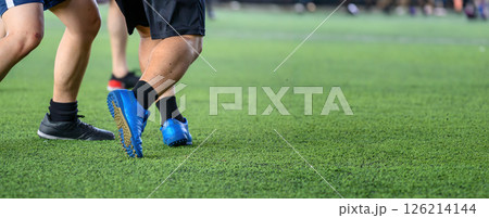 Soccer players in action during game on grass field focusing on their legs and ball, showing movement and competition in sports setting Soccer players in action during game on grass field focusing on their legs and ball, showing movement and competition in sports setting 126214144