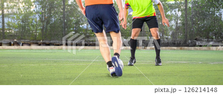 Soccer players in action during game on grass field focusing on their legs and ball, showing movement and competition in outdoor sports setting 126214148