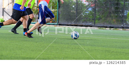 Soccer players in action on green grass field focusing on their legs and ball during game with motion and energy 126214385