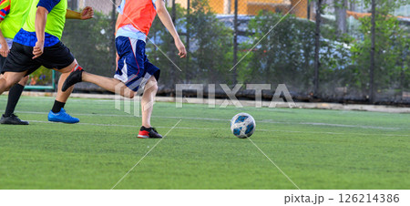 Soccer players in action on green grass field focusing on their legs and ball during game with vibrant sportswear and dynamic movement 126214386