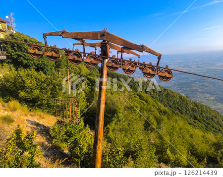 Old cable car system rests under a vibrant blue sky overlooking lush green hills 126214439