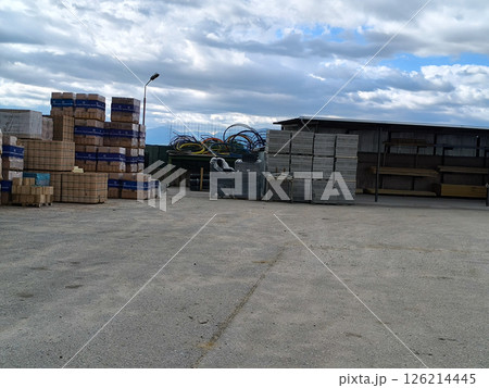 Stacks of building materials and tools under a cloudy sky in a construction yard during the afternoon Stacks of building materials and tools under a cloudy sky in a construction yard during the afternoon 126214445