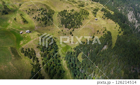 Expansive green hills and rustic cabins nestled in a serene landscape at golden hour 126214514