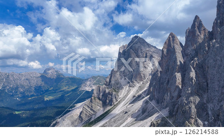 Serene mountain landscape under a vibrant blue sky adorned with fluffy clouds during a sunny day in the Dolomites 126214588
