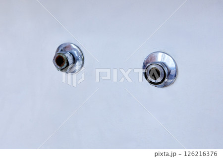 Two exposed metal pipe outlets with chrome escutcheons protrude from smooth white wall after removal of old wall mounted faucet, showing slight corrosion. 126216376