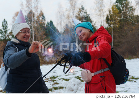 Celebrating winter joy with sparklers in a snowy forested area on a chilly day 126216764
