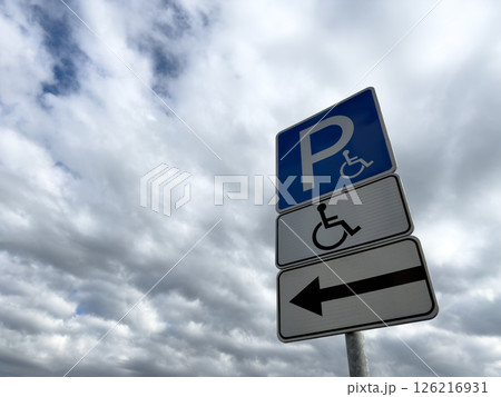 Handicap parking sign with directional arrow on cloudy day, indicating accessible parking for people with disabilities, promoting inclusion and barrier free infrastructure 126216931