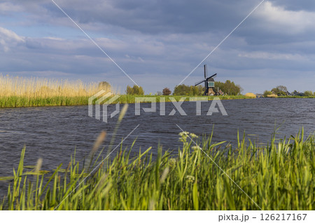 Traditional Dutch windmill standing on the bank of a canal in Brandwijk, Netherlands Traditional Dutch windmill standing on the bank of a canal in Brandwijk, Netherlands 126217167