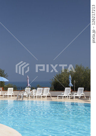 Inviting swimming pool overlooking the sea under a clear blue sky Inviting swimming pool overlooking the sea under a clear blue sky 126217213