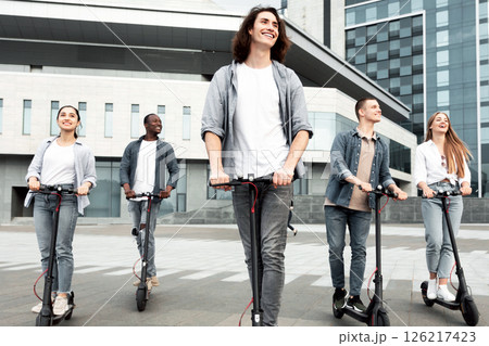 Best Buddies. Full length portrait of five stylish multiracial teenagers riding electric push scooters in urban area 126217423
