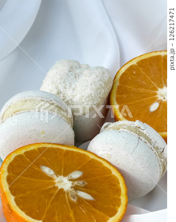 Delicate macarons and orange slices on light drapery Delicate macarons and orange slices on light drapery 126217471