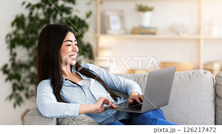 Favorite Pastime. Cheerful Asian Woman Relaxing With Laptop On Couch, Browsing Internet Or Watching Movies, Enjoying Weekend At Home Favorite Pastime. Cheerful Asian Woman Relaxing With Laptop On Couch, Browsing Internet Or Watching Movies, Enjoying Weekend At Home 126217472