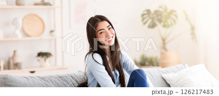 Home Comfort. Portrait Of Beautiful Asian Girl Posing On Sofa In Living Room, Smiling At Camera 126217483