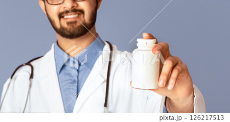 Smiling Indian doctor showing jar of pills on violet background, mockup for design. Selective focus. Panorama Smiling Indian doctor showing jar of pills on violet background, mockup for design. Selective focus. Panorama 126217513