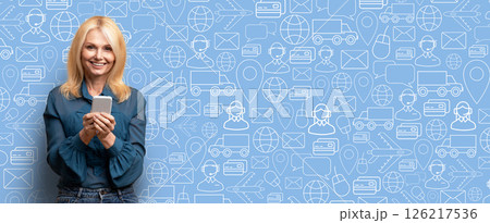A smiling buyer holds a smartphone, engaging with an online shopping application. The backdrop features icons related to commerce, emphasizing a modern digital shopping experience. A smiling buyer holds a smartphone, engaging with an online shopping application. The backdrop features icons related to commerce, emphasizing a modern digital shopping experience. 126217536