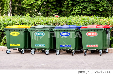 Green plastic dumpsters on a city street with inscription on russian: " Plastic", "Other", "Paper", "Glass", "Press on" 126217743