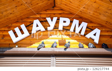 Facade with signboard of fast food restaurant Shawarma. Inscription in Russian: Shawarma Facade with signboard of fast food restaurant Shawarma. Inscription in Russian: Shawarma 126217744