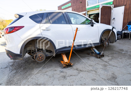 Car without wheels and lift up by jack stand .Waiting for tire replacement. Car without wheels and lift up by jack stand .Waiting for tire replacement. 126217748