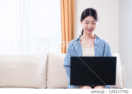 家でリラックスをしてパソコンを使う若い女性 126217762