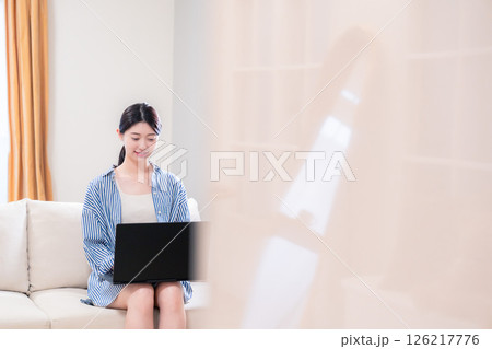 家でリラックスをしてパソコンを使う若い女性 126217776