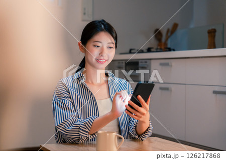 夜遅くに笑顔でスマホを使う若い女性 夜遅くに笑顔でスマホを使う若い女性 126217868