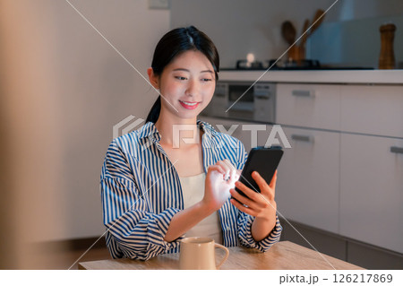 夜遅くに笑顔でスマホを使う若い女性 夜遅くに笑顔でスマホを使う若い女性 126217869