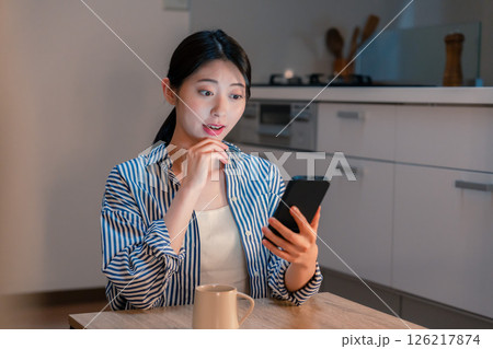 夜遅くに笑顔でスマホを使う若い女性 夜遅くに笑顔でスマホを使う若い女性 126217874