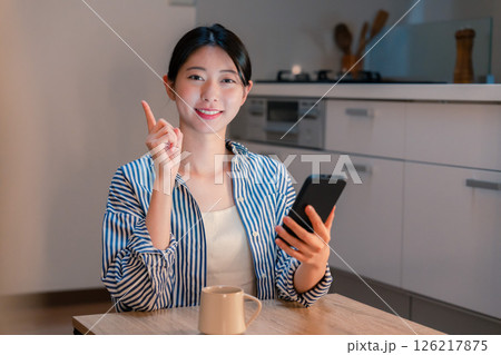 夜遅くに笑顔でスマホを使う若い女性 126217875