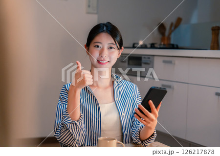 夜遅くに笑顔でスマホを使う若い女性 126217878