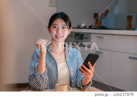 夜遅くに笑顔でスマホを使う若い女性 夜遅くに笑顔でスマホを使う若い女性 126217879