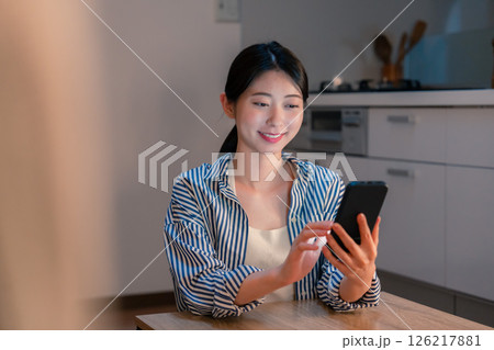夜遅くに笑顔でスマホを使う若い女性 126217881