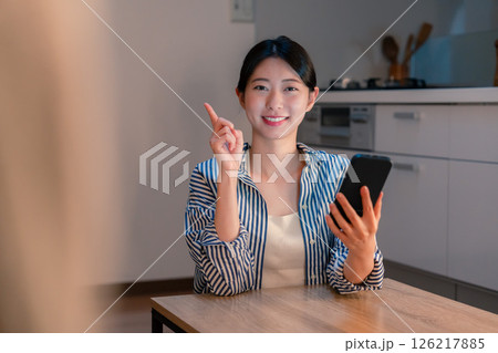 夜遅くに笑顔でスマホを使う若い女性 夜遅くに笑顔でスマホを使う若い女性 126217885