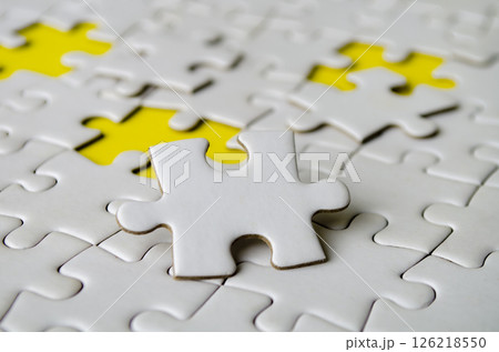 Side close up of white jigsaw puzzle pieces placed on a bright yellow background with customizable space on jigsaw for text or ideas. Side close up of white jigsaw puzzle pieces placed on a bright yellow background with customizable space on jigsaw for text or ideas. 126218550