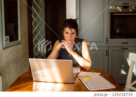 Freelancer female having online video call using laptop sitting in home kitchen. Remote work. Working from home concept. Freelancer female having online video call using laptop sitting in home kitchen. Remote work. Working from home concept. 126218739