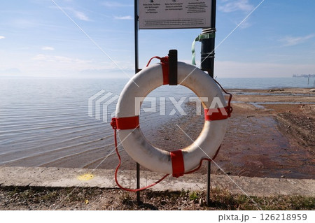 A white life preserver is on a post by the water 126218959