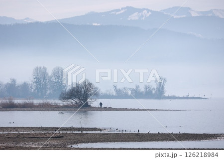 A man is fishing in a lake with a cloudy sky in the background A man is fishing in a lake with a cloudy sky in the background 126218984