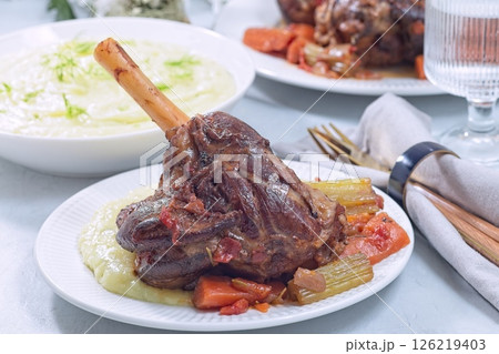 Delicious braised lamb shanks with vegetables served with horseradish and fennel mashed potatoes 126219403