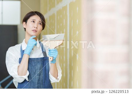 石膏ボードにパテを塗るDIYする女性 石膏ボードにパテを塗るDIYする女性 126220513