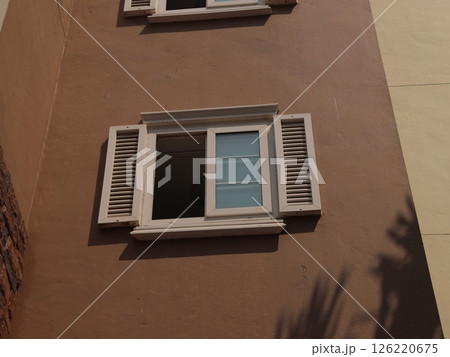 Charming and Inviting Window with Decorative Shutters Set Against a Soft Beige Wall Charming and Inviting Window with Decorative Shutters Set Against a Soft Beige Wall 126220675