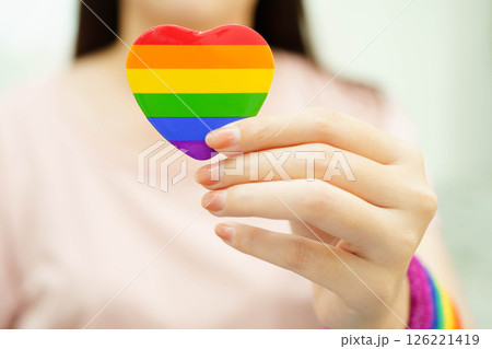 Asian woman holding LGBT heart with rainbow flag. 126221419