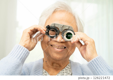 Asian senior woman wearing ophthalmic vision eye test and using optical trial frame. Asian senior woman wearing ophthalmic vision eye test and using optical trial frame. 126221472