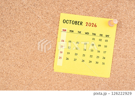 Yellow calendar sheet for October 2026 with thumbtack on board. 126222929