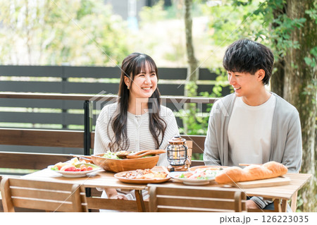 ウッドデッキ・テラス席・バルコニー席で食事するカップル・夫婦（グランピング・ベランピング） 126223035