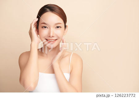A beautiful young Asian woman with clean, fresh skin against a beige background. Skincare, facial treatment, cosmetology, beauty, and spa. An elegant portrait of an Asian woman. 126223772