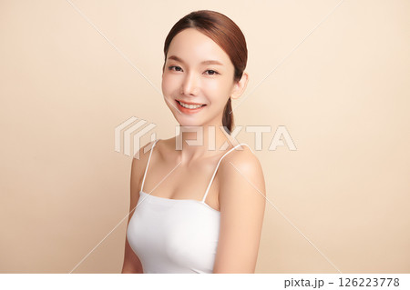 A beautiful young Asian woman with clean, fresh skin against a beige background. Skincare, facial treatment, cosmetology, beauty, and spa. An elegant portrait of an Asian woman. 126223778