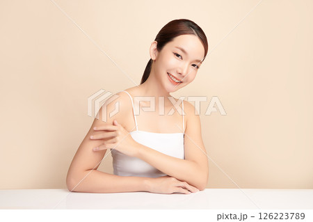 A beautiful young Asian woman with clean, fresh skin against a beige background. Skincare, facial treatment, cosmetology, beauty, and spa. An elegant portrait of an Asian woman. 126223789