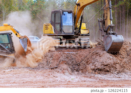 Excavators, bulldozers clear construction site, moving soil, debris on clear day. Excavators, bulldozers clear construction site, moving soil, debris on clear day. 126224115