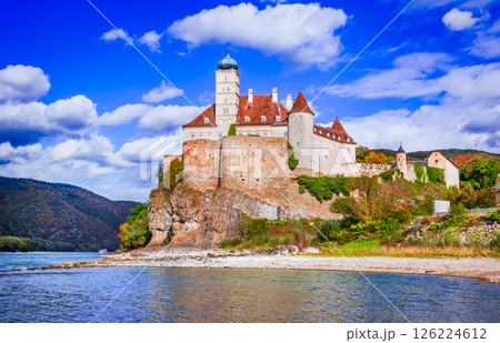 Austria, Schonbuhel Castle stands atop a rocky cliff, surrounded by golden autumn foliage, overlooking the Danube River, Wachau Valley. 126224612