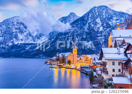 Hallstatt, Austria. Serene Alpine village with snow-covered rooftops on tranquil lake, breathtaking mountain backdrop winter twilight Hallstatt, Austria. Serene Alpine village with snow-covered rooftops on tranquil lake, breathtaking mountain backdrop winter twilight 126225096